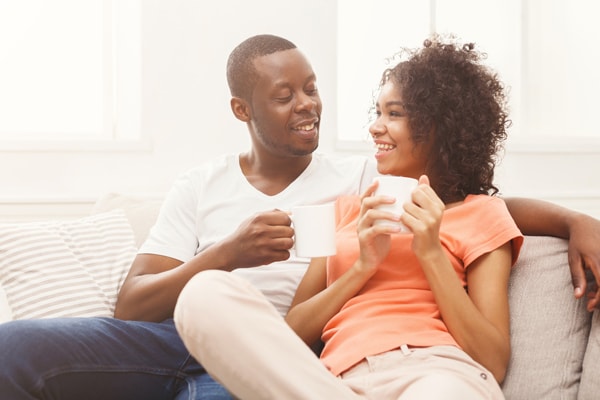 Happy african-american couple drinking coffee at cozy home.