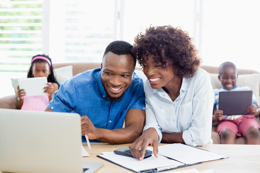 Family happily using electronics in their home.