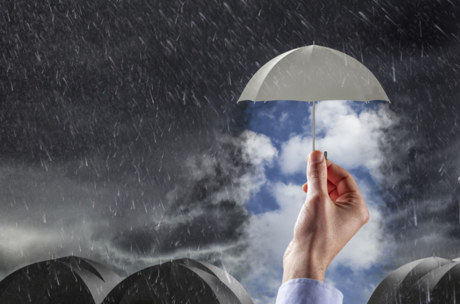 Rainy sky with tiny umbrella over a hand.