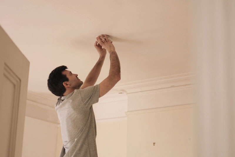 HVAC technician replacing the batteries in homeowner's smoke detector.