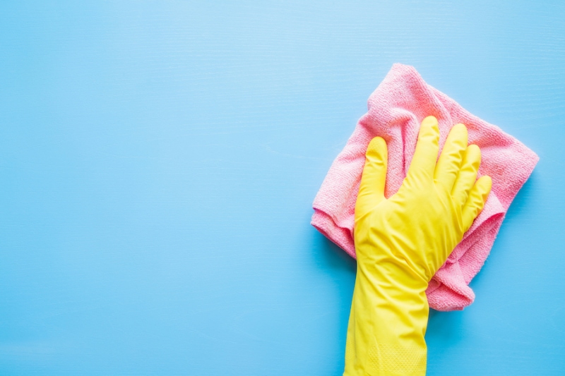 Does an AC Kill Mold?Employee hand in rubber protective glove with microfiber rag wiping blue table, wall or floor surface in room, bathroom, kitchen. Early spring or regular cleanup. Commercial cleaning company concept.