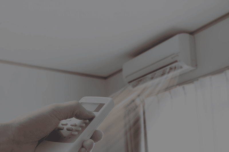 Image of a hand using a remote to turn on the ductless AC unit.