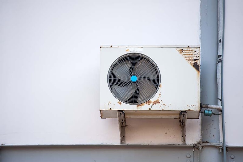 Old mounted air conditioner with rust to represent when it is time to purchase a new air conditioner.