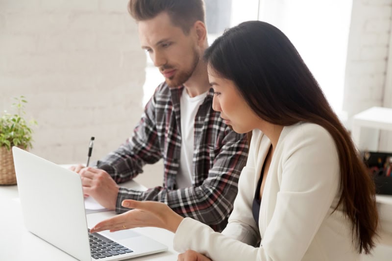 Couple looking at an AC maintenance checklist on their laptop.