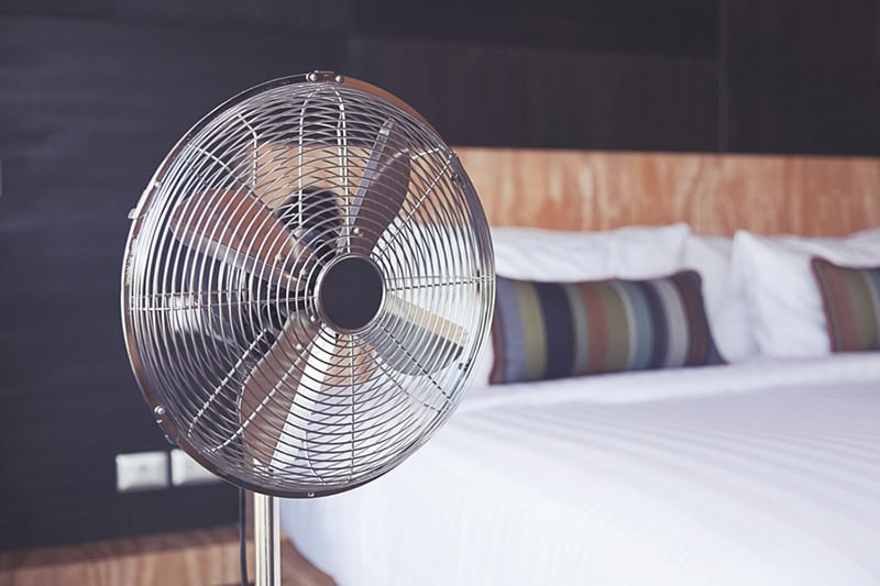 Clean osculating fan sitting next to bed to represent improving your indoor air quality.