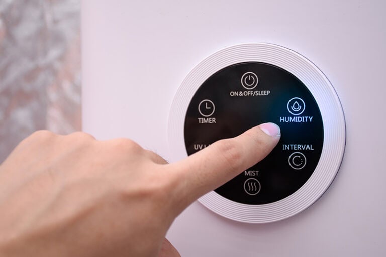 Close up man hand pressing the digital humidifier button on a smart humidifier in a smart home or green house.