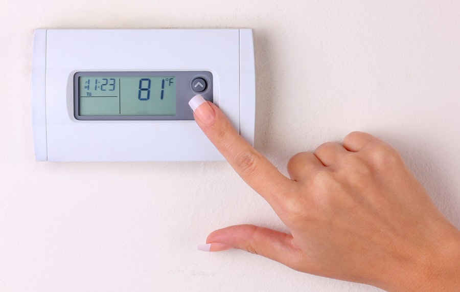 Female homeowner setting her programmable thermostat.