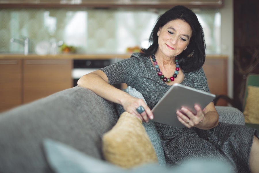 Female homeowner reading about factors to consider when buying a heat pump.